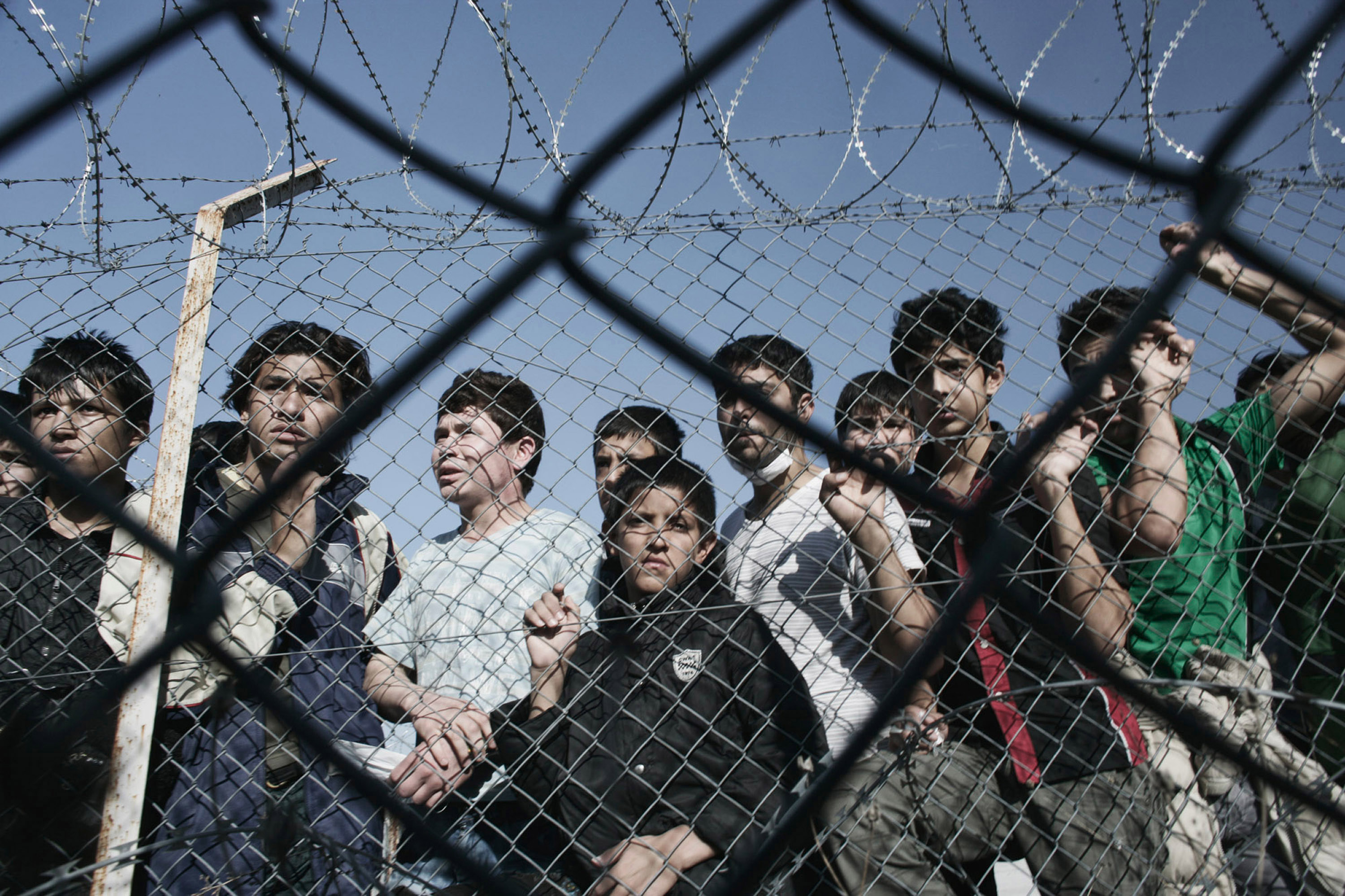 young illegal immigrants standing behind a fence at a detention center, in the Greek village of Filakio near the Greek-Turkish border.
