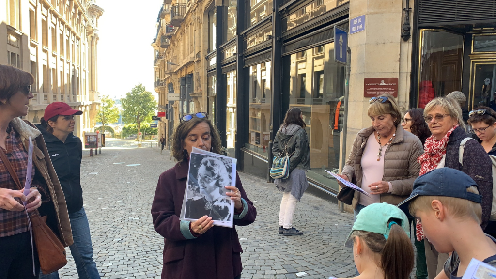 Floriane Nikles montre la photo d'Antoinette Quinche aux participants à la promenade, devant sa plaque commémorative
