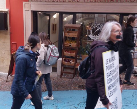 Des manifestants défilent devant une boutique de Neuchâtel.