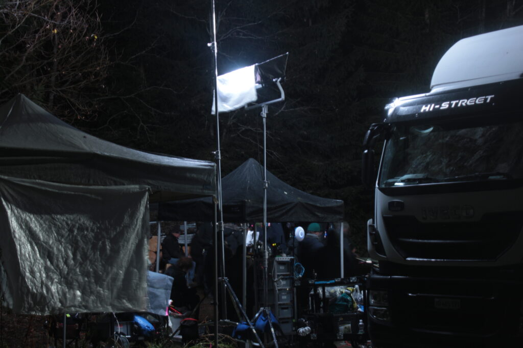 Un camion et du matériel de tournage sont éclairés par une source de lumière artificielle.