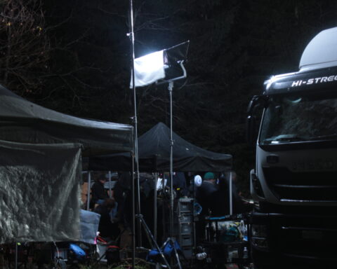 Un camion et du matériel de tournage sont éclairés par une source de lumière artificielle.